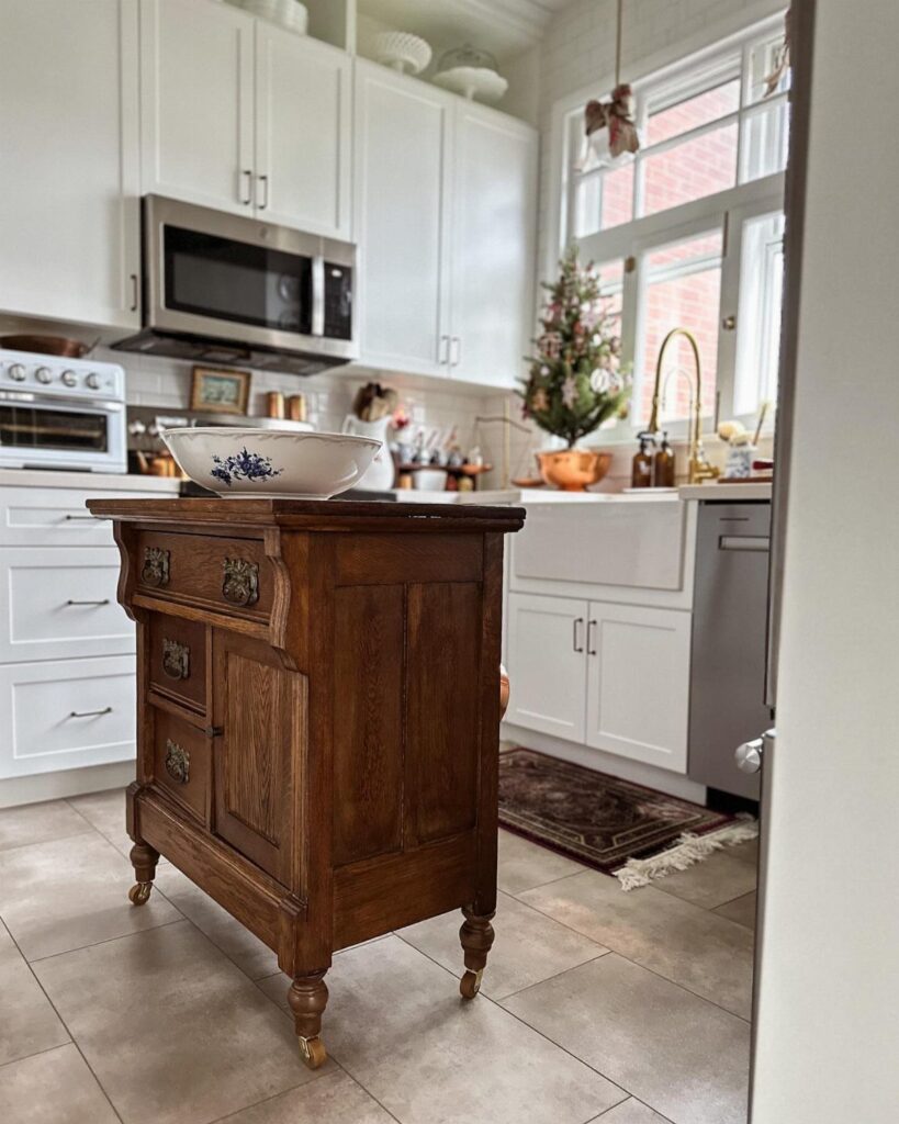 Antique wooden dresser repurposed as a kitchen island in a bright white kitchen setting.