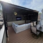 A modern rooftop deck with wicker seating, a dining set, and an outdoor kitchen area.